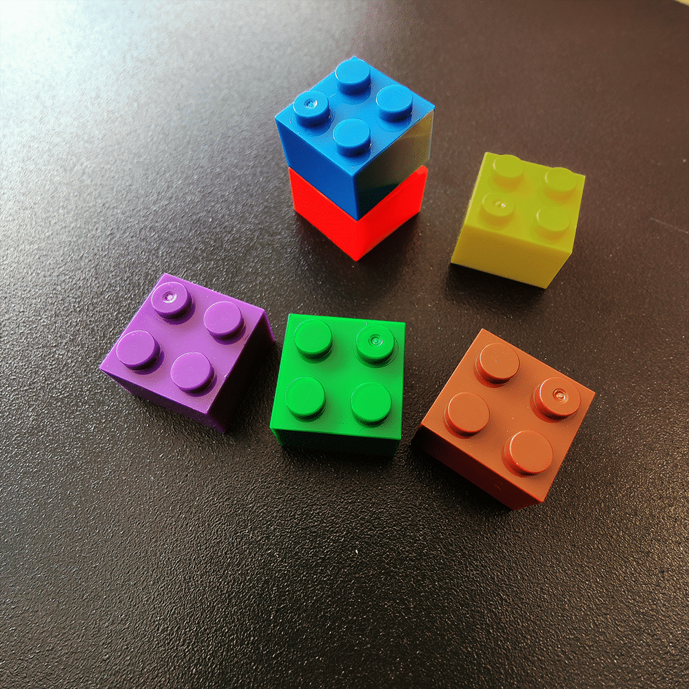 Een aantal gekleurde lego steentjes met een klein magneetje