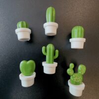 een groep koelkastmagneten van kleine cactussen in witte potten