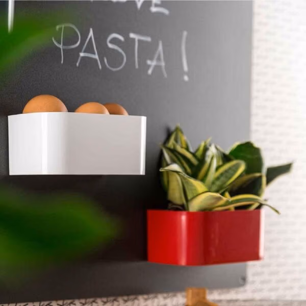 Twee magnetische bakjes van 12 centimeter in het rood en wit op een zwart magneetbord in de keuken